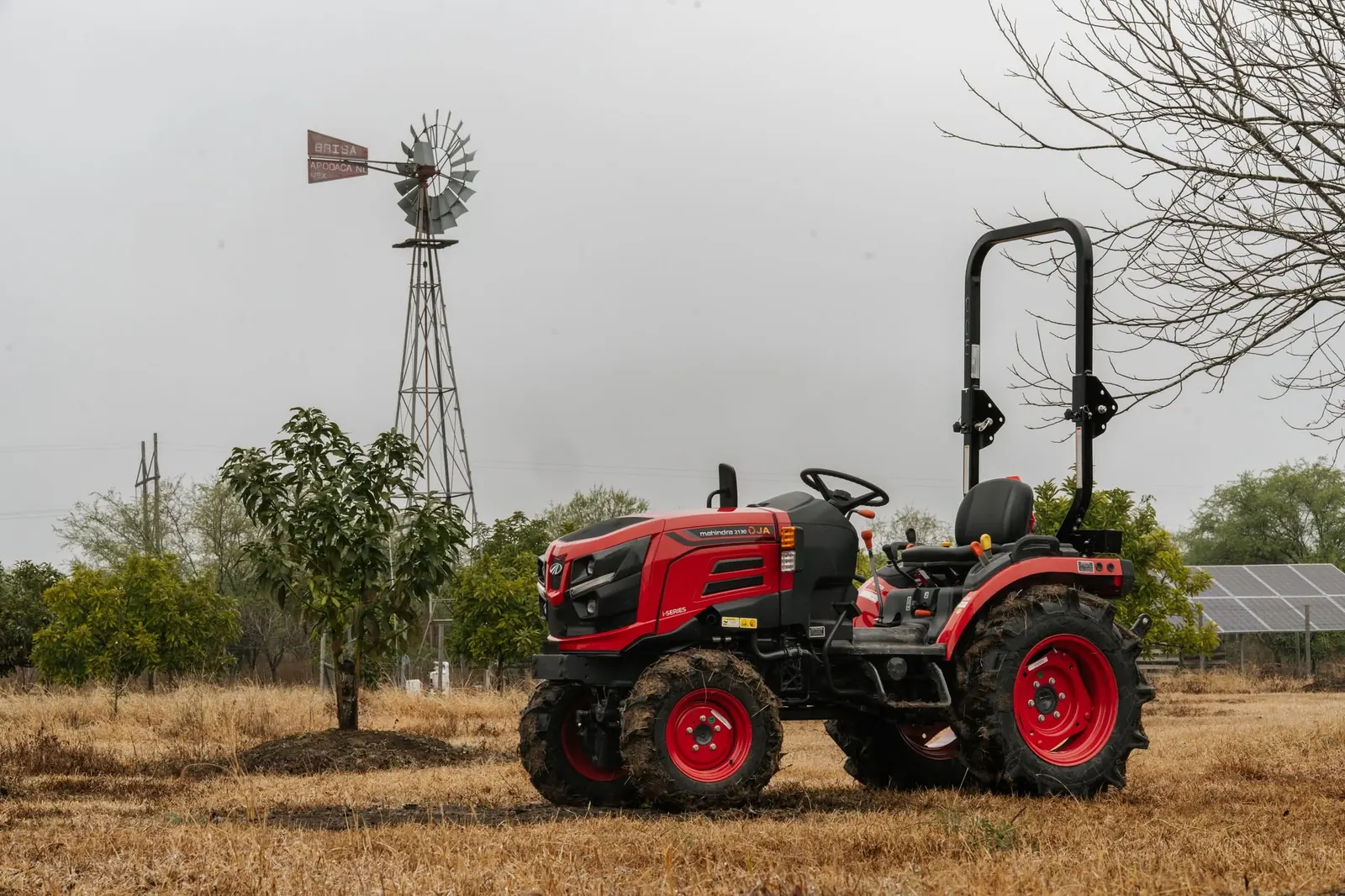 Mahindra OJA 2130 en un huerto, junto a un molino de viento